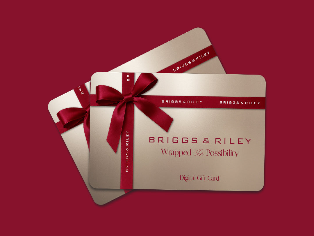 Two Briggs & Riley gift cards with a red ribbon bow, displayed on a solid dark red background.