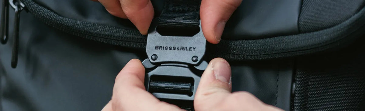 Close-up of a Briggs & Riley backpack buckle being fastened.